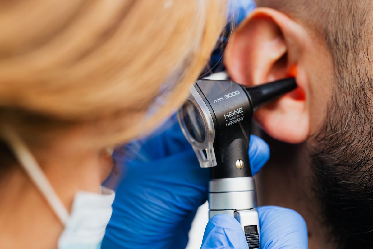 Profissional de saúde examinando o ouvido de um paciente com otoscópio