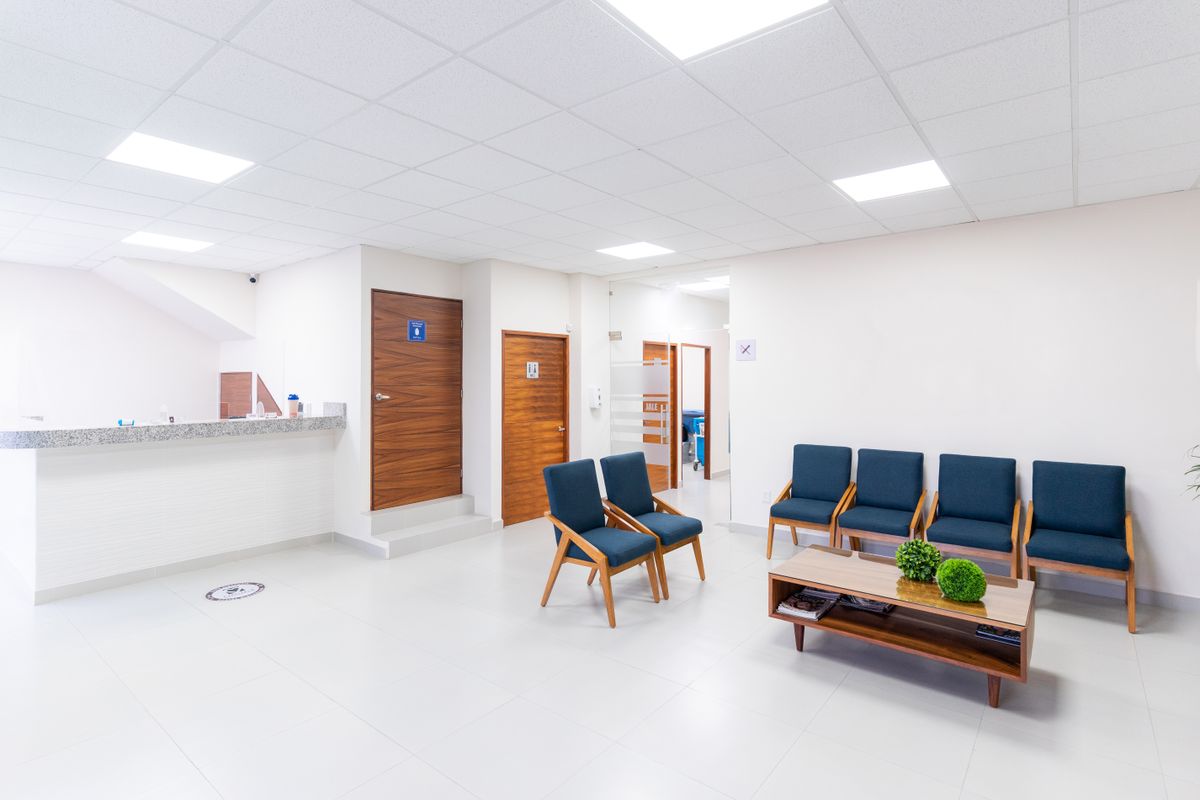 Sala de espera de uma clínica com as portas das salas de atendimento ao fundo