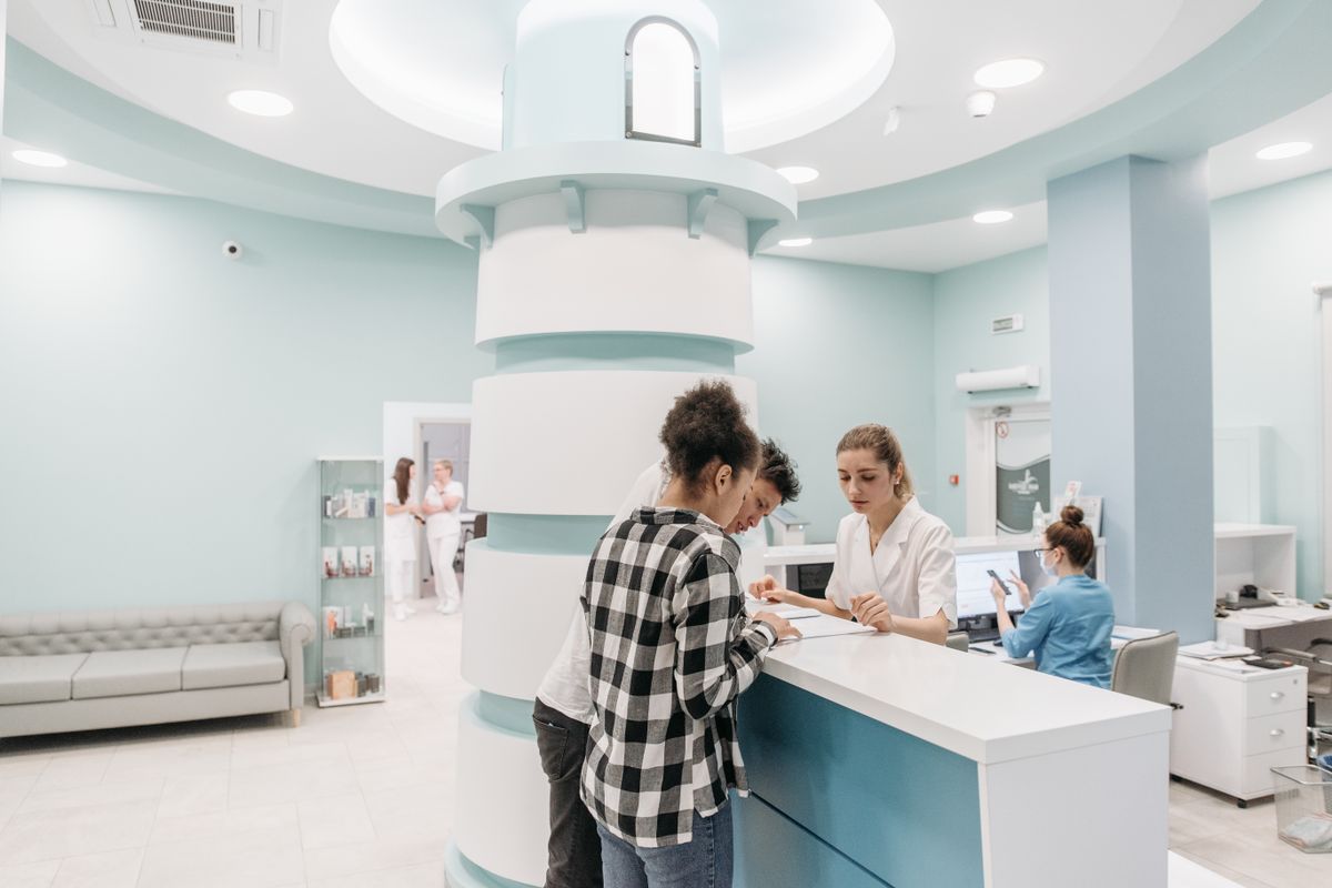 Pacientes sendo atendidos no balcão de recepção de uma clínica