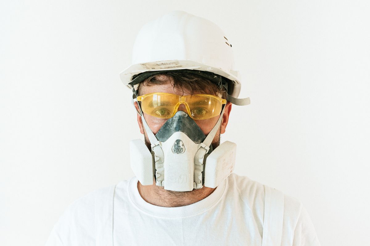 Trabalhador com capacete, óculos de proteção e respirador semifacial